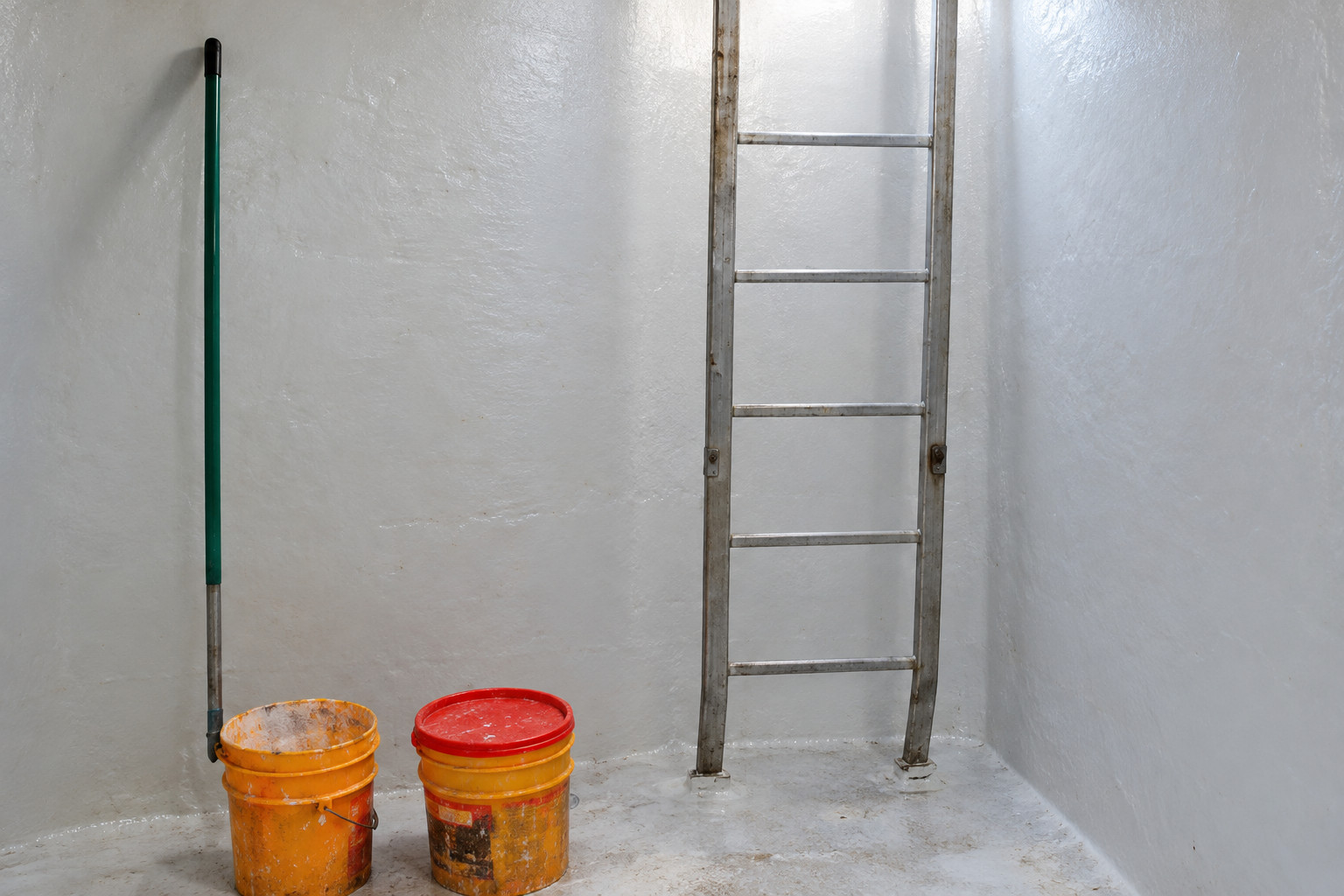 Interior de un tanque con escalera de acceso y utensilios de limpieza. Imagen regenerada de referencia.